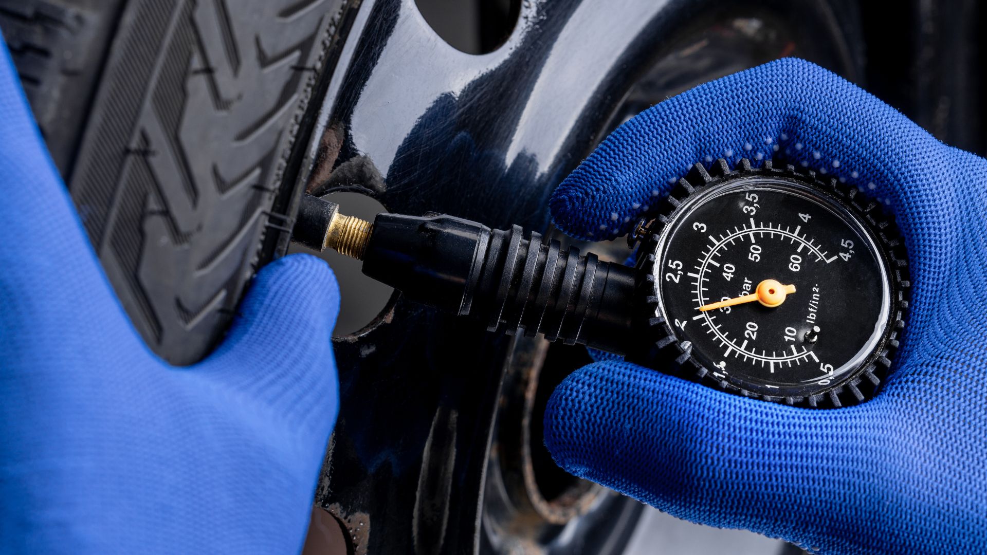 a person in blue gloves is changing a tire pressure gauge.