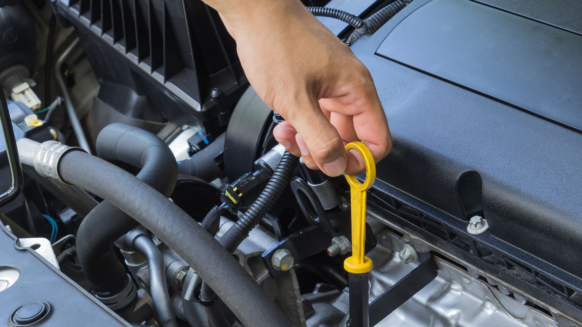 a person holding a wrench in front of a car engine.