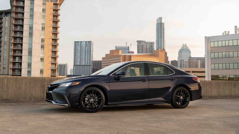 a black car parked in front of a city skyline.