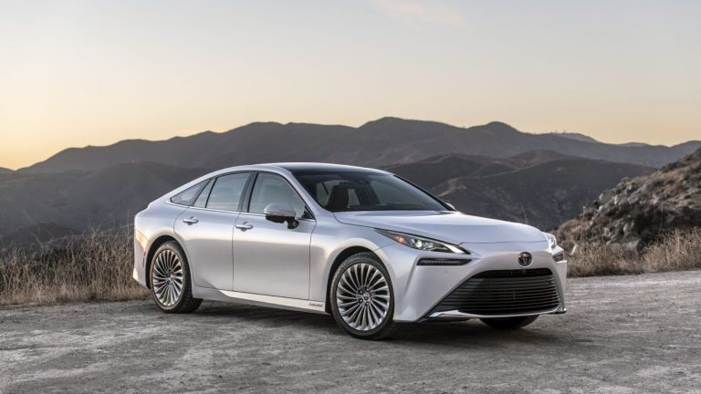 a silver car parked on top of a dirt field.