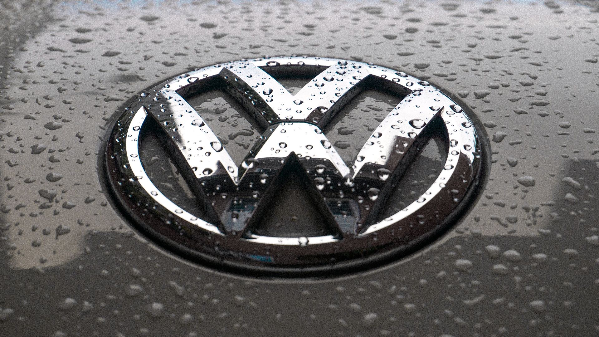 a close up of a volkswagen emblem on a wet surface.