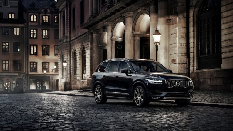 a black volvo suv parked on a cobblestone street.