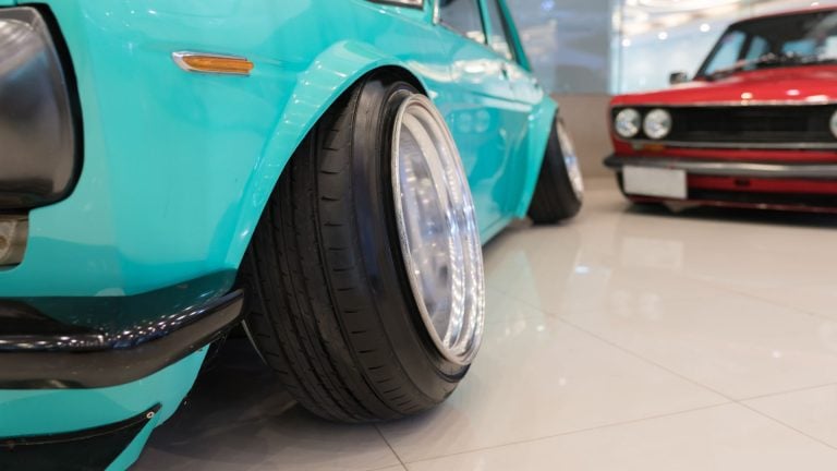 a blue car parked in a showroom next to a red car.