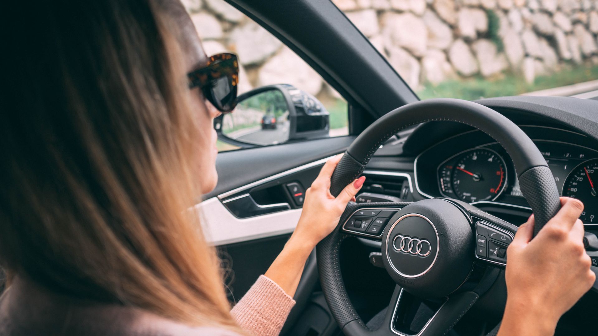 a woman driving a car with her hands on the steering wheel.