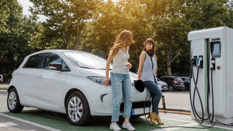 women waiting to charge electric car