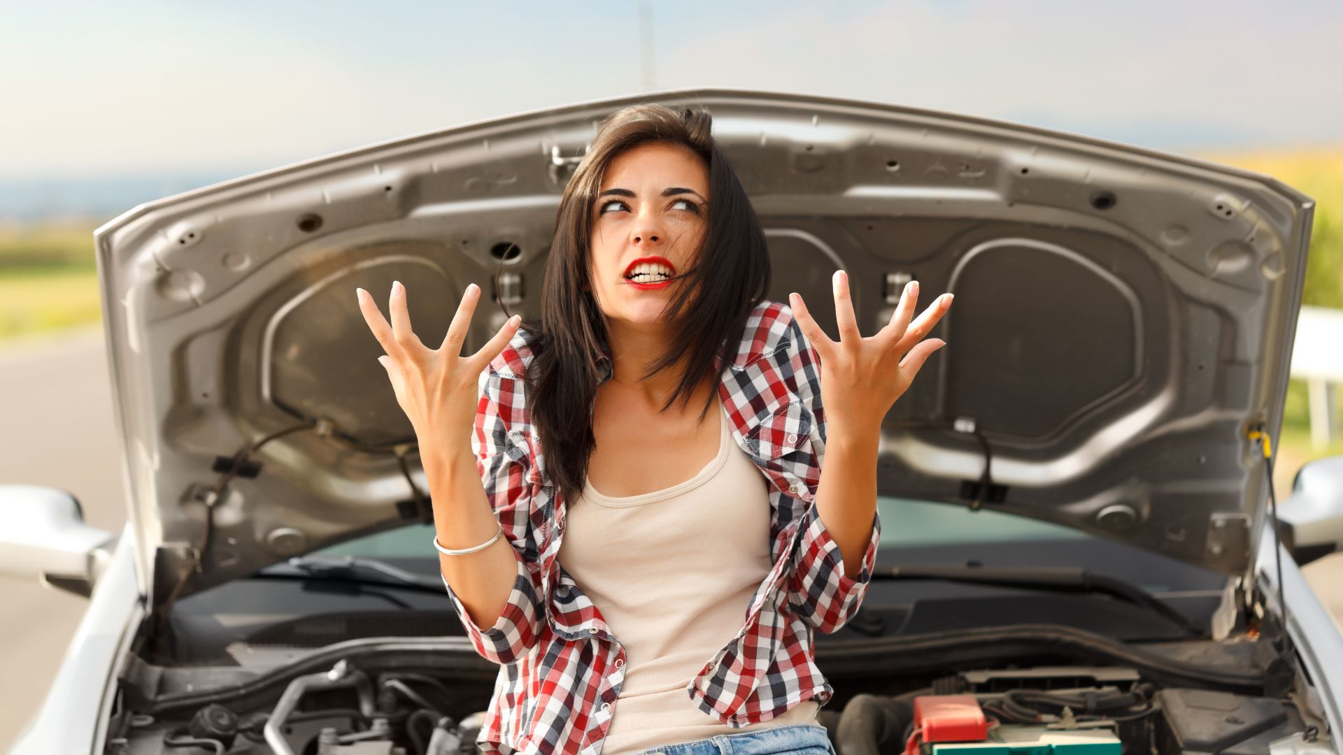 a woman standing in front of a car with her hands in the air.